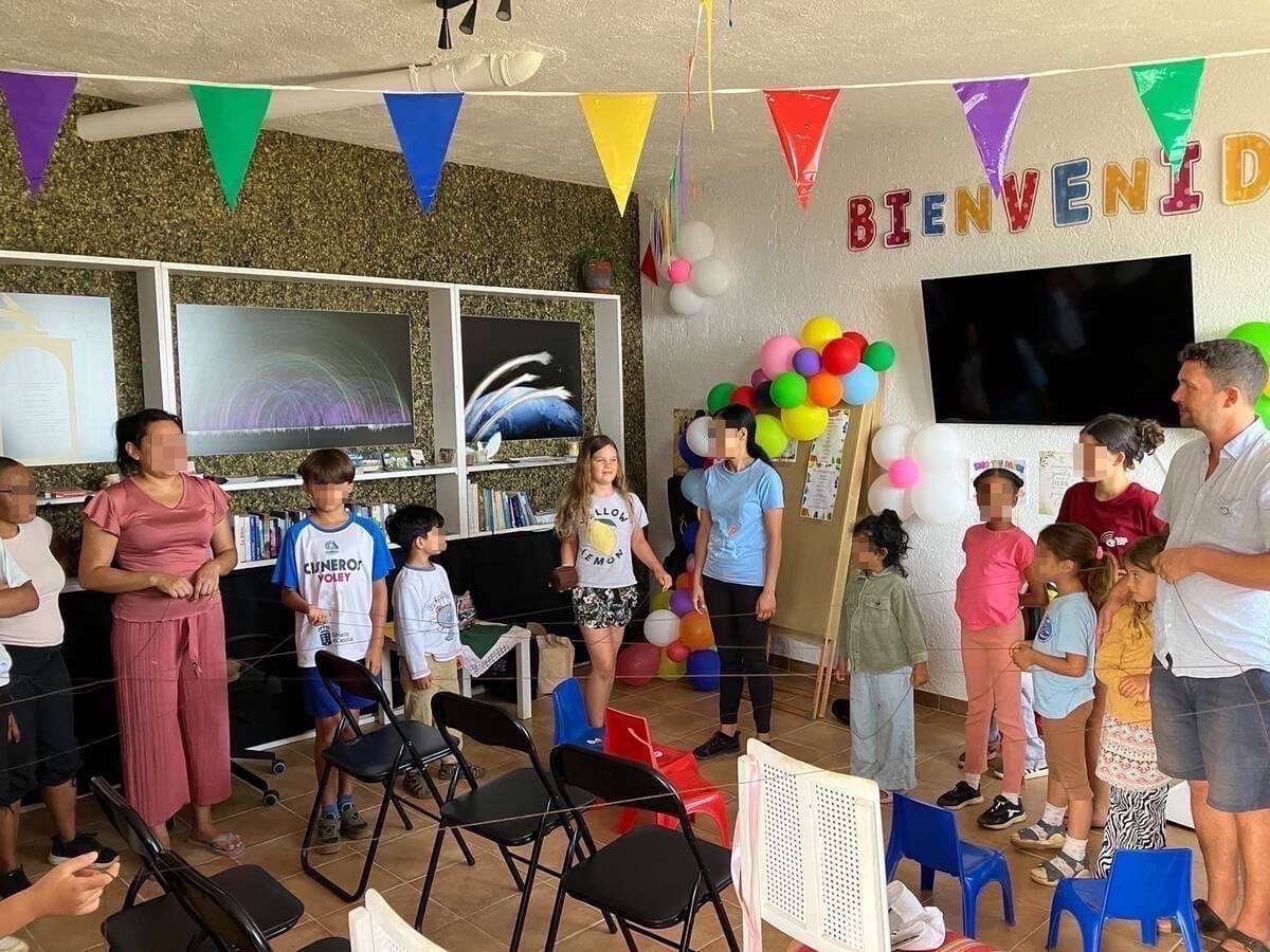 Niños y adultos en el salón comunitario decorado de la Finca Maranatha